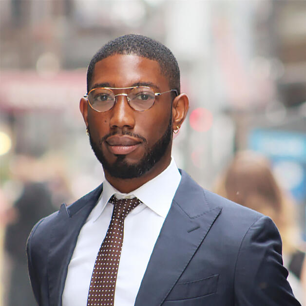 Andrew Davis Headshot Headshot of an African-American man on the street in New York City dressed in a blue suit with white shirt and brown tie
